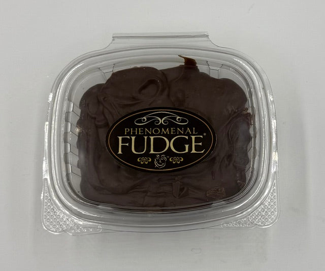 Chocolate fudge in a clear plastic clamshell container with a black and gold label reading 'Phenomenal Fudge'.