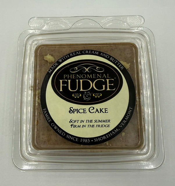 A square package labeled 'Phenomenal Fudge Spice Cake' in a clear plastic clamshell container on a plain light background.